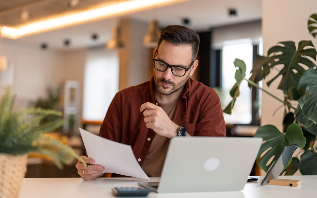 Worker Looking At Papers At Computer