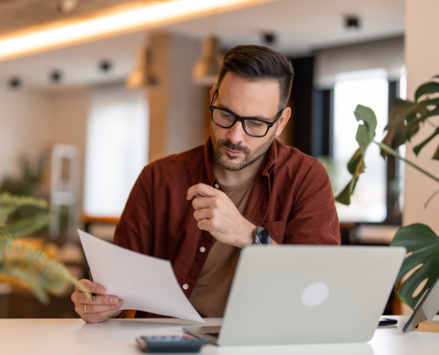 Worker Looking At Papers At Computer